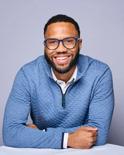 Portrait of Brandon I. King, PhD, founder of The BOL Group LLC, smiling in glasses and a blue quarter-zip sweater